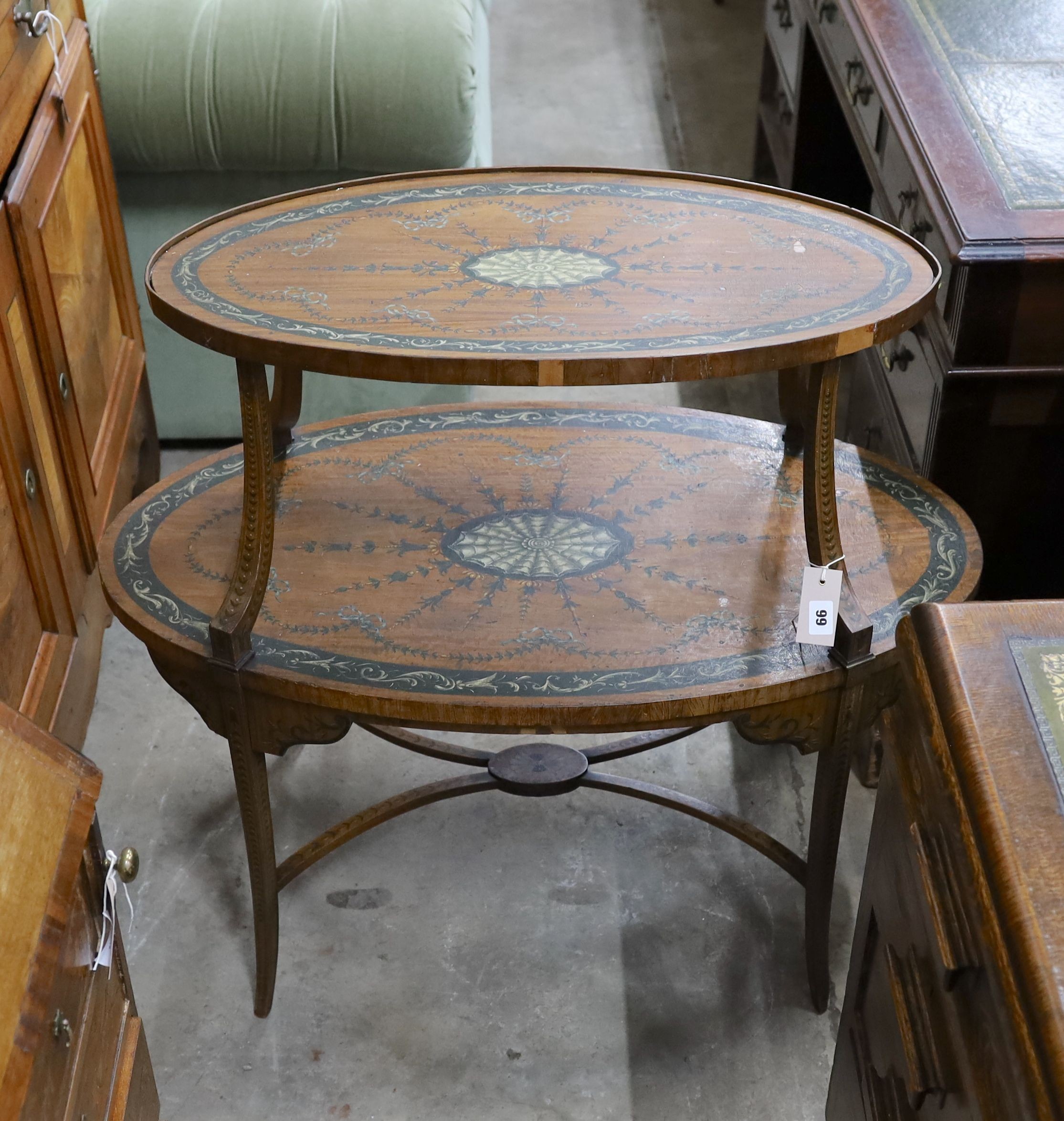 An Edwardian Sheraton revival oval painted satinwood two tier etagere, width 90cm, depth 50cm, height 82cm